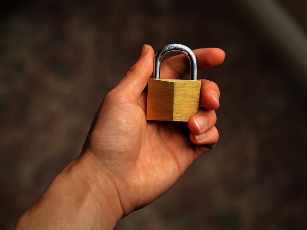 Bàn tay cầm một ổ khóa bằng đồng